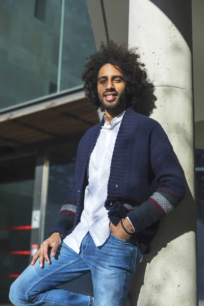 Een jonge mooie modieuze Afro-Amerikaanse staat in de buurt van een pilaar. Een student in jeans en een blauw jasje met een trendy kapsel — Stockfoto