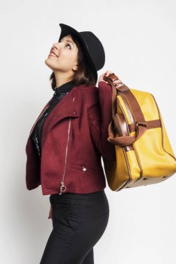 Beyaz arka plan karşı bir çanta tutarken ayakta şık bir kadın rahat giyim Yan görünümü