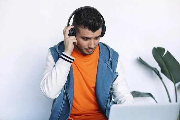 Vidám fiatalember fejhallgatón hallgatta a zenét, miközben ül a munkahelyén — Stock Fotó