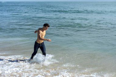 Genç yakışıklı kaslı adam güneşli bir günde sahilde