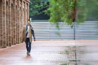 Sokakta yürüyen kışlık giysiler giyen genç bir adam. Şehir arka planında modern saç stili olan genç bir adam.