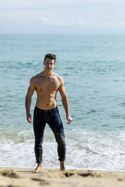 Young handsome muscular man on seashore in a sunny day — ストック写真