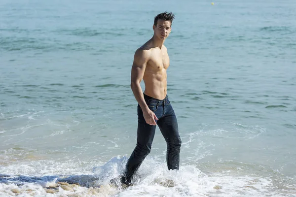 Young handsome muscular man on seashore in a sunny day — ストック写真