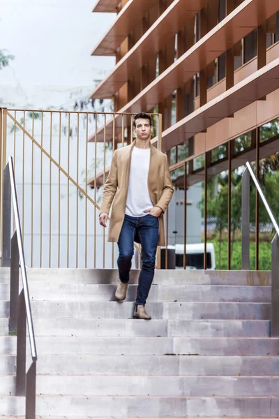 Een jonge man daalt door de trap in de stad met een vacht. — Stockfoto