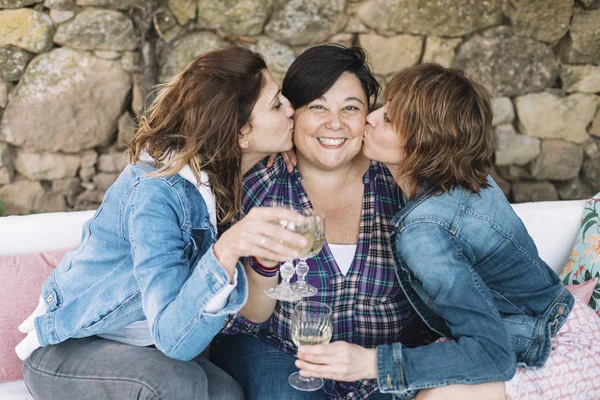 Closeup portrait of three woman having fun kissing friend relaxing sitting outdoors while smiling — Zdjęcie stockowe