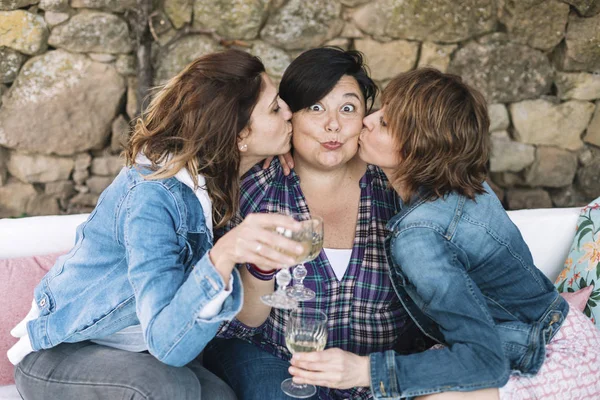 Closeup portrait of three woman having fun kissing friend relaxing sitting outdoors while smiling — Zdjęcie stockowe