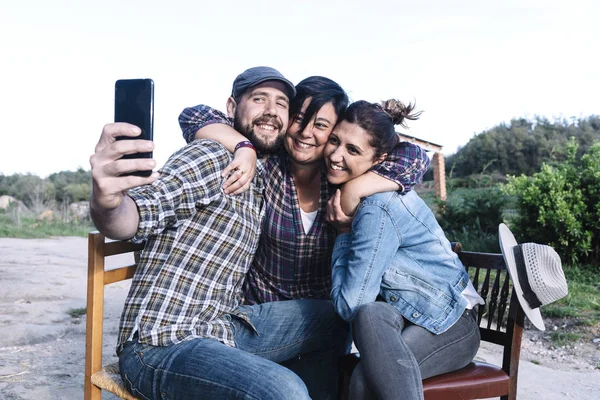 Un grupo de amigos sentados al aire libre mientras se toman una selfie con amigos . — Foto de Stock
