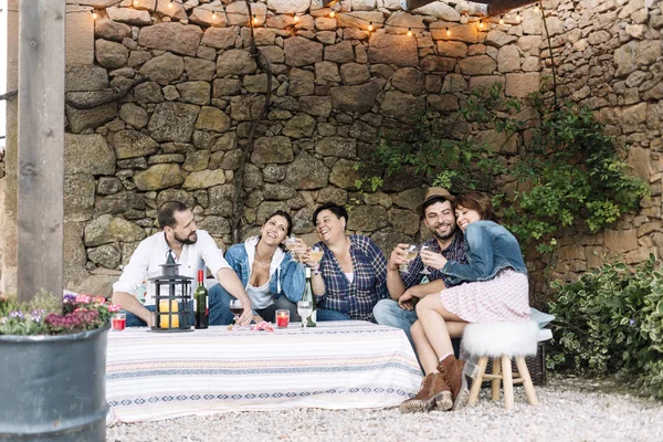 Retrato de jovens felizes sentados juntos e rindo enquanto desfrutam de uma festa com vinho na mesa . — Fotografia de Stock