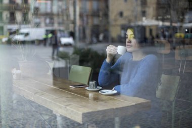 Genç kadın bir kafede pencereden dışarı bakıyor
