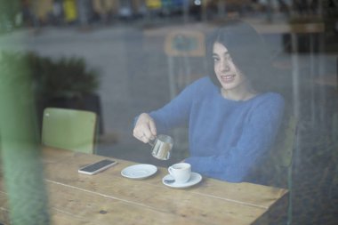 Genç kadın bir kafede pencereden dışarı bakıyor