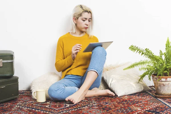 Porträt einer Frau, die mit einem digitalen Tablet auf dem Boden des Wohnzimmers sitzt — Stockfoto