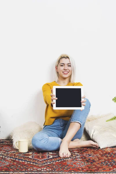 Kamera bakarken tablet pc gösteren gülümseyen kadın