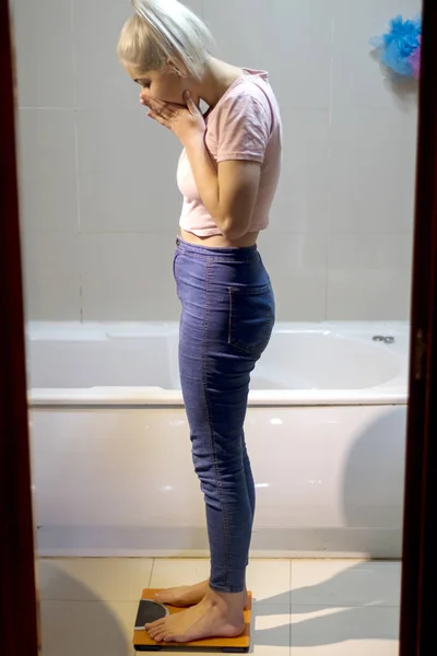 Ritratto di una giovane donna fitness sorpresa in piedi su squame — Foto Stock