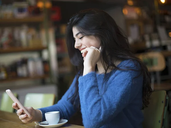 Junge Frau in Freizeitkleidung unterhält sich im Café per Video-Chat mit ihrem Smartphone — Stockfoto