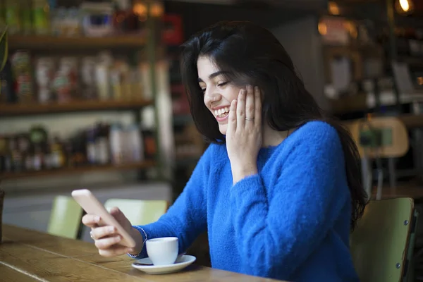 Junge Frau in Freizeitkleidung unterhält sich im Café per Video-Chat mit ihrem Smartphone — Stockfoto