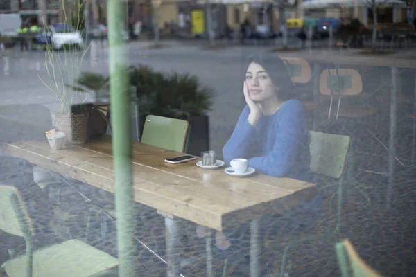 Genç kadın bir kafede pencereden dışarı bakıyor