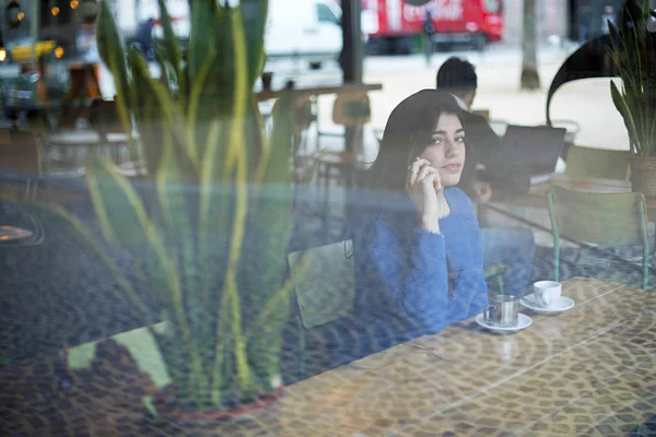 Kafede otururken akıllı telefonla konuşan kadın pencereden görüldü