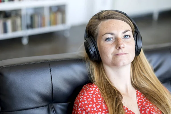 Hermosa mujer escuchando música en auriculares inalámbricos — Foto de Stock