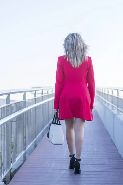 Elegante mujer rubia con chaqueta roja y falda caminando sobre el fugitivo a ninguna parte — Foto de Stock