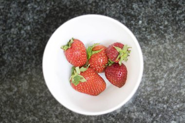 Beyaz bir tabakta çilek manzarasının üstünde.