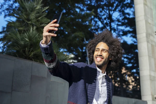 Jonge afro Amerikaanse man die lacht gelukkig nemen selfie zelfportret foto met mobiele telefoon — Stockfoto