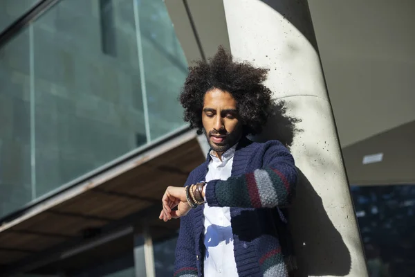 Jonge knappe man met afro haar controleren van de tijd op pols horloge — Stockfoto