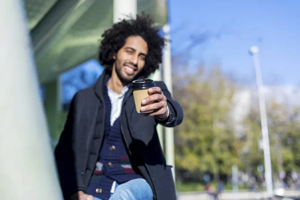 Portret van vrolijke knappe afro man in casual kleding poseren voor de camera bebaarde jongeman houden afhaalkoffie in de hand — Stockfoto