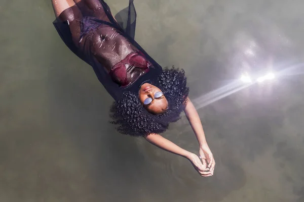 Bella giovane donna afroamericana galleggiante in una piscina d'acqua — Foto Stock