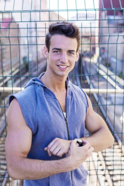 Genç gülen koşucu antrenmandan sonra kol saatini kontrol ediyor.