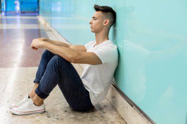 Depresyondaki genç adam zemin sokak metrosunda oturuyor.