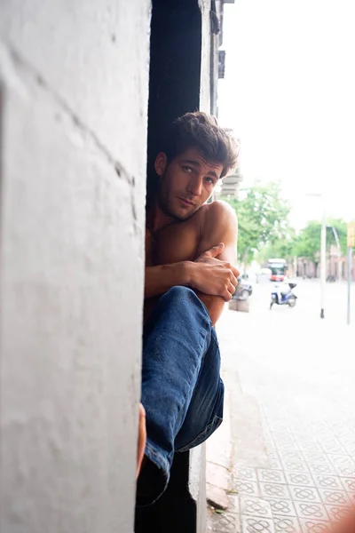 A young man sitting anxious outdoors