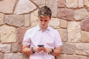 Sarışın genç erkek dışarıda cep telefonu kullanıyor.