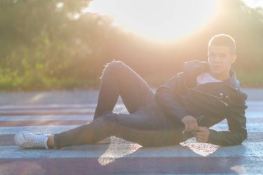 Neşeli genç adam yolda yatıyor.