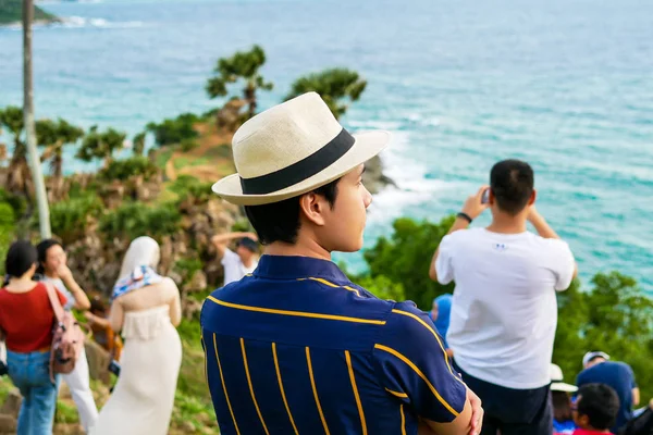A man tourist with Panama hat is looking the beautiful natural landscape of the sea on the top view point of  Promthep Cape in Phuket, Thailand