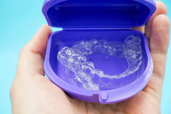 Mão está segurando dentes de plástico transparente retentor na caixa set isolado no céu azul — Fotografia de Stock