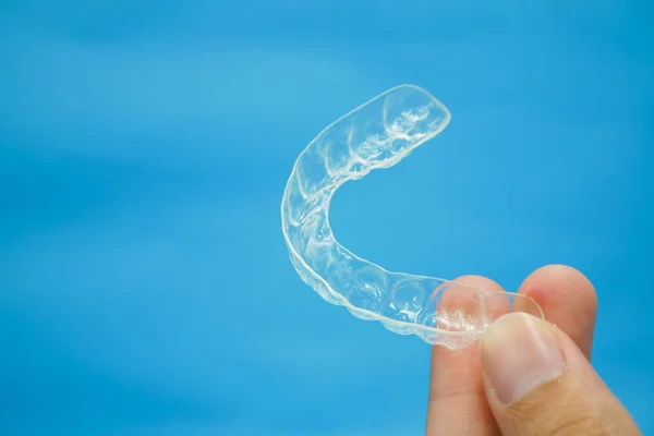 Mână care ține dinții de reținere din plastic clar — Fotografie, imagine de stoc