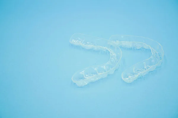 Hand holding clear plastic retainer teeth that isolated on blue background — Stock Photo, Image