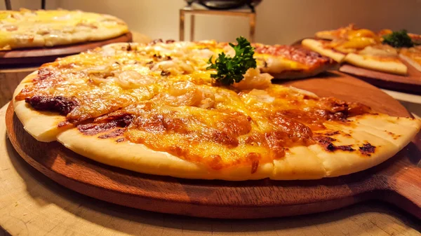 トッピングの多くからなる木製のプレート上のピザ — ストック写真