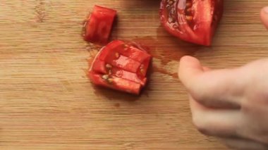 Kadın elleri bambu dilimleme tahtasında kırmızı sulu domates kesiyor. Salata için dilimler halinde keskin bıçaklı yakın plan..