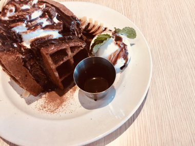 Lezzetli ev yapımı waffle, taze meyve, çikolatalı dondurma, üstüne krema ve bir dilim muz.