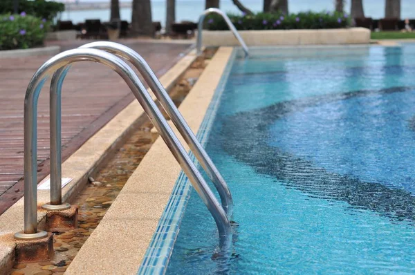 Grab bar ladder in Swimming pool, Blue spa swimming pool with clean water and beachfront background.