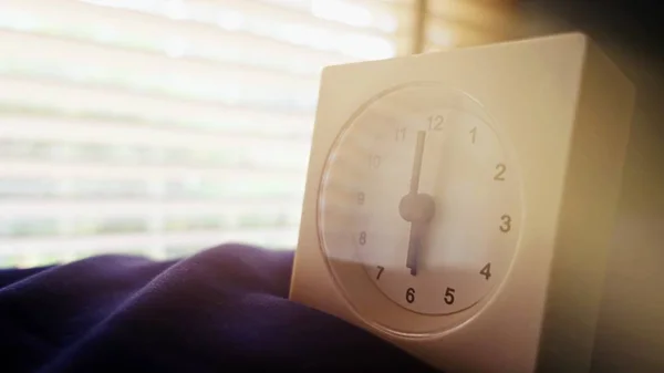 old memory time concept, retro square clock timed at 6 o\'clock on the bed with sun light from window