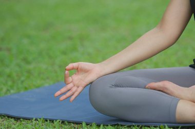 Lotus duruşu yakın, parkta yoga, açık havada hafif ve sağlıklı bir kadın. Sağlıklı yaşam tarzı ve rahatlama kavramı.