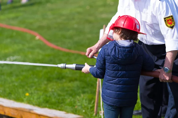 Strażak Pomoc Młody Chłopak Firehose Podczas Demonstracji — Zdjęcie stockowe