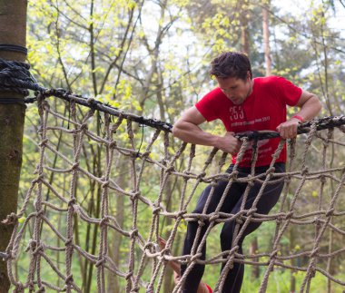 Oldenzaal, Hollanda - 7 Mayıs 2017: bilinmeyen Erkek atlet bir ip çalıştırmak bir hayatta kalma net üzerinden tırmanma