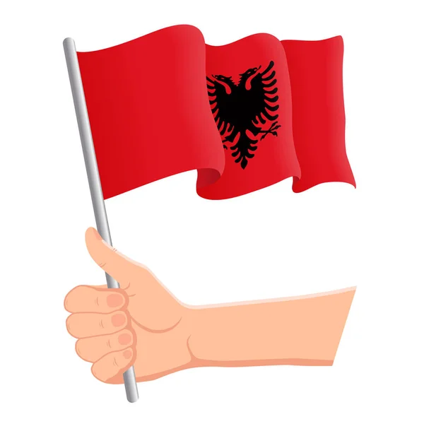 Рука держит и размахивает государственным флагом Албании. Вентиляторы, День независимости, патриотическая концепция. Векторная иллюстрация — стоковый вектор