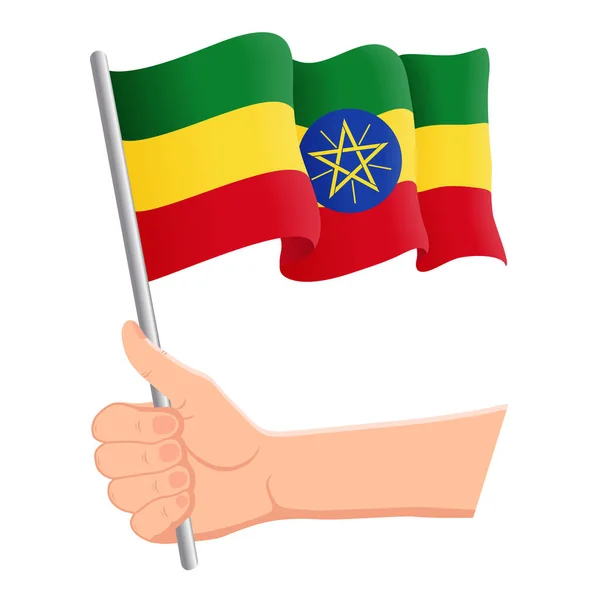 Mano sosteniendo y agitando la bandera nacional de Etiopía. Aficionados, día de la independencia, concepto patriótico. Ilustración vectorial — Archivo Imágenes Vectoriales