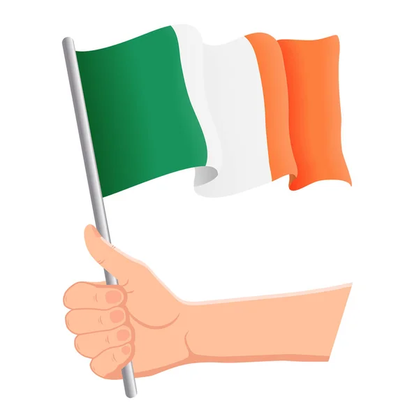 Рука держит и машет национальным флагом Ирландии. Вентиляторы, День независимости, патриотическая концепция. Векторная иллюстрация — стоковый вектор