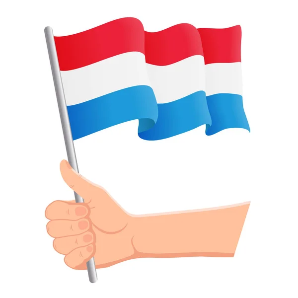 Mano sosteniendo y agitando la bandera nacional de Luxemburgo. Aficionados, día de la independencia, concepto patriótico. Ilustración vectorial — Vector de stock