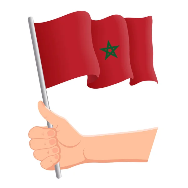 Hand hält und die marokkanische Nationalflagge schwenkt. Fans, Unabhängigkeitstag, patriotisches Konzept. Vektorillustration — Stockvektor